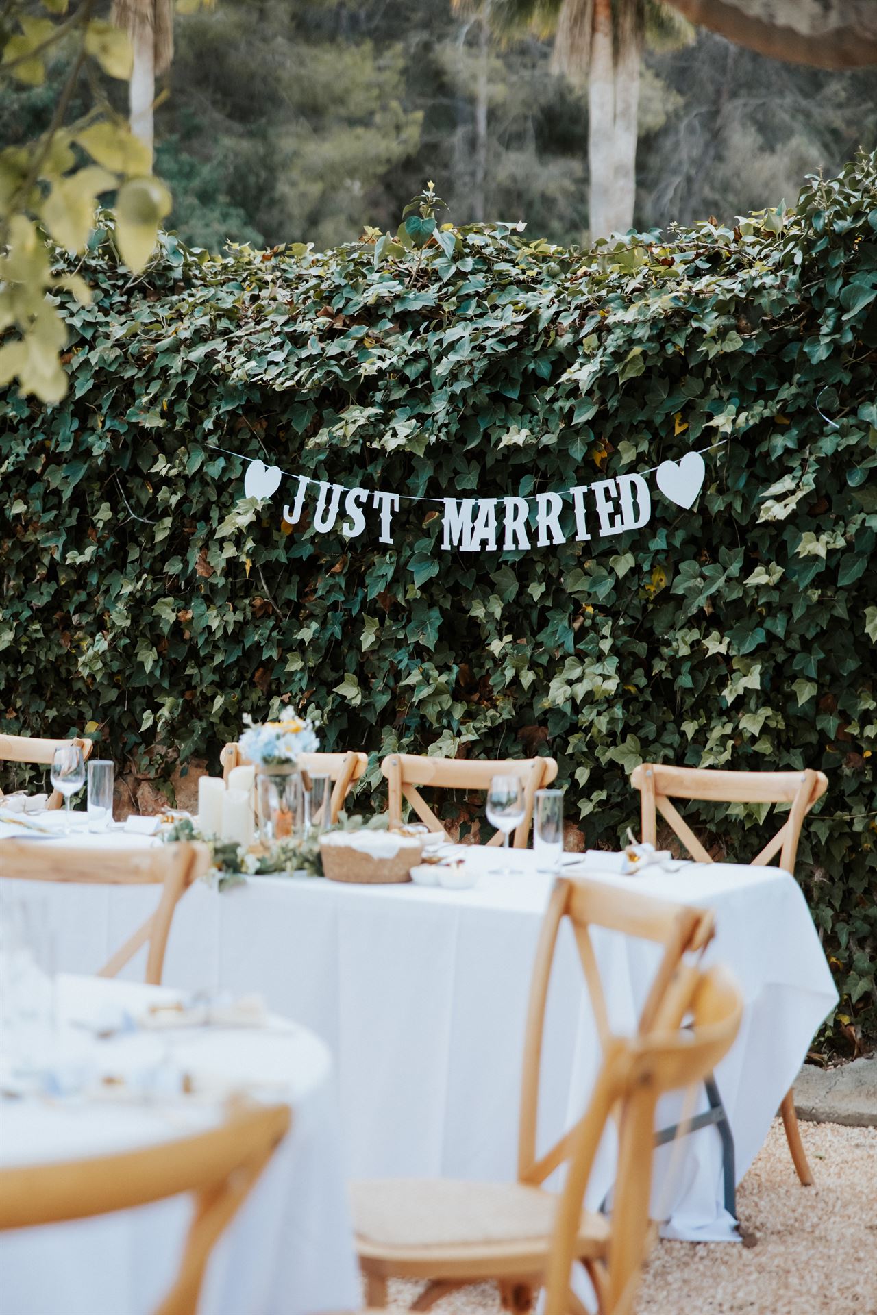 A 'Just Married' sign on an ivy hedge above dinner tables