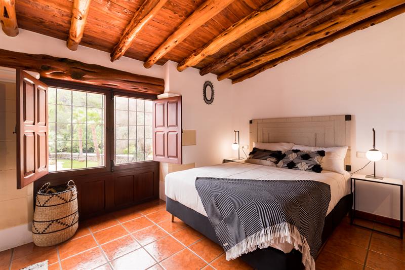 Master suite with a large bed, wooden shutters and beamed ceiling