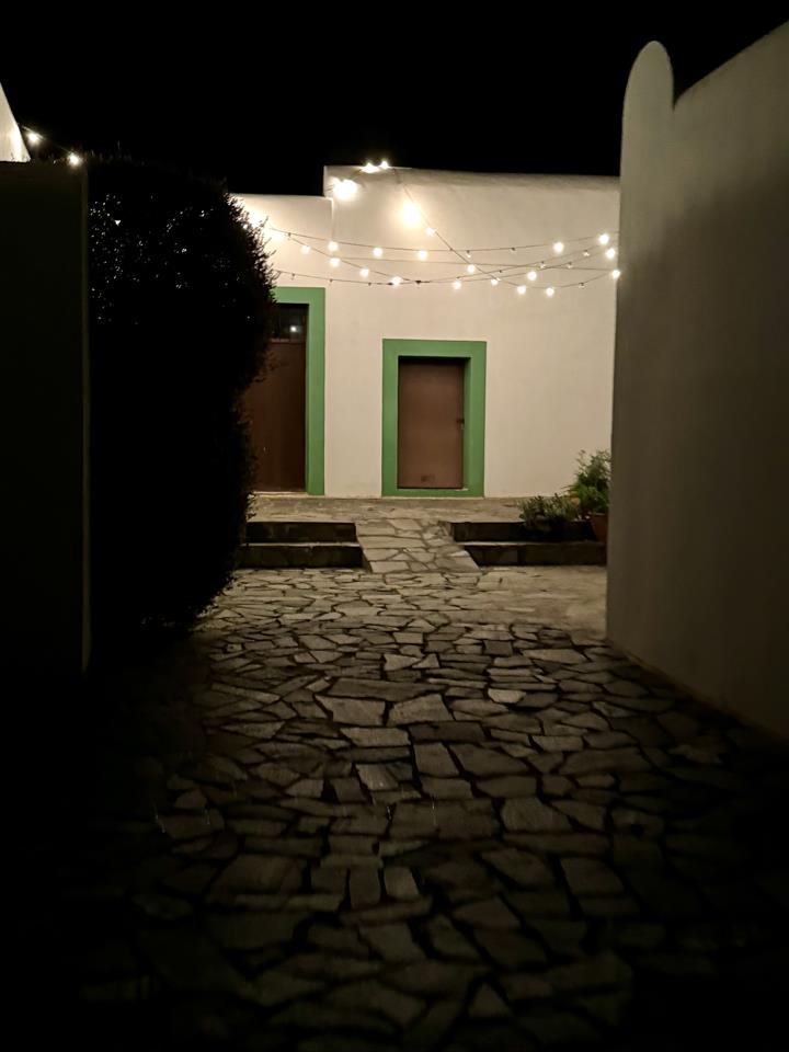 The whitewashed courtyard at night under string lights